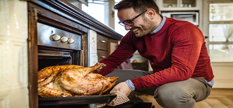 man taking out baked turkey from the oven