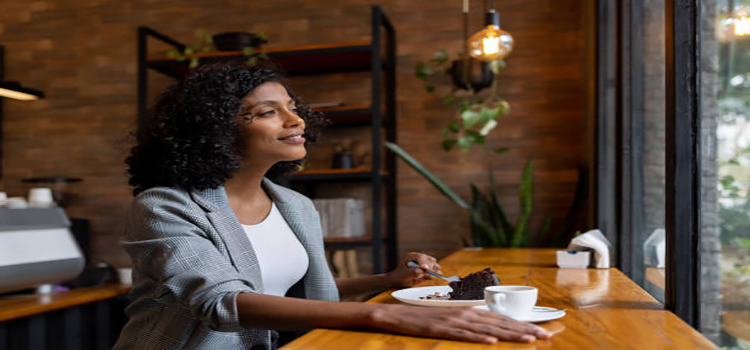 woman at cafe eating cake while drinking a cup of coffee