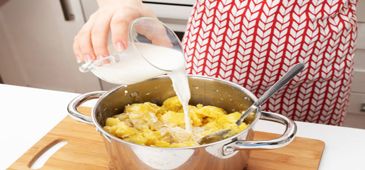 woman pouring milk on mashed potatoes