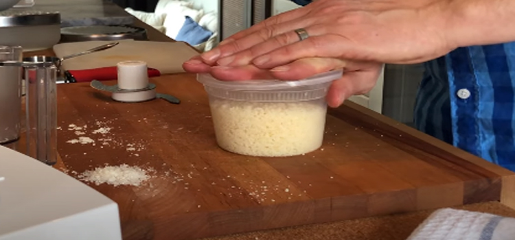 man storing grated parmesan on a container