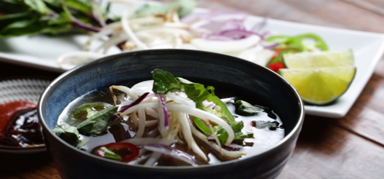 Bowl of Beef Pho with ingredients on the background