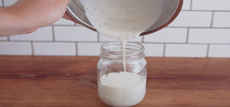 pouring ranch dressing on a jar for storing