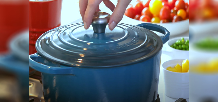 a woman's hand opening the lid of Dutch Oven