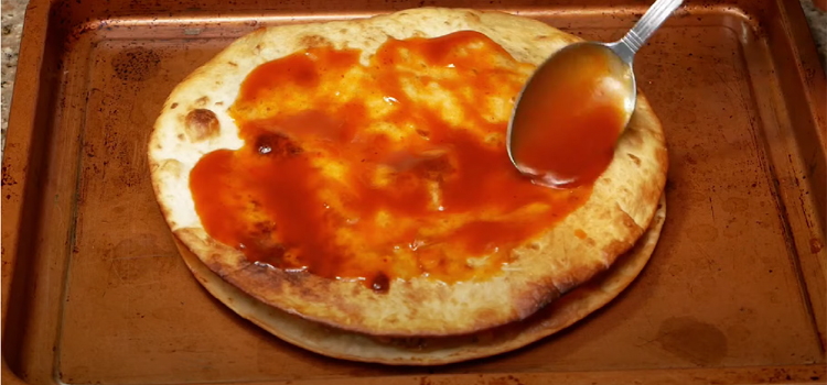 putting sauce on a pizza