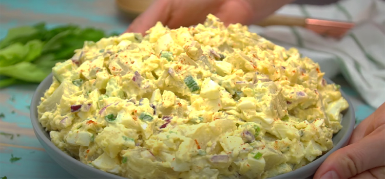 Hand Holding Bowl of Deviled Egg Potato Salad