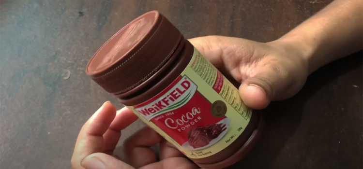 Hand Holding Jar of Cocoa powder