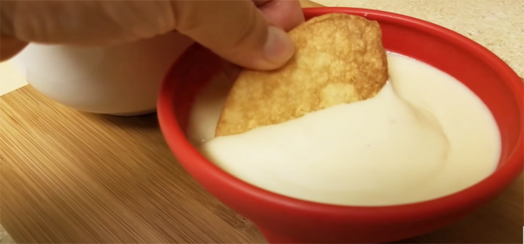 dipping tortilla on a white cheese