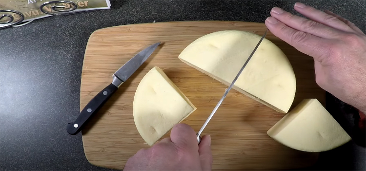 Top View Image of a Person Slicing Gouda Cheese