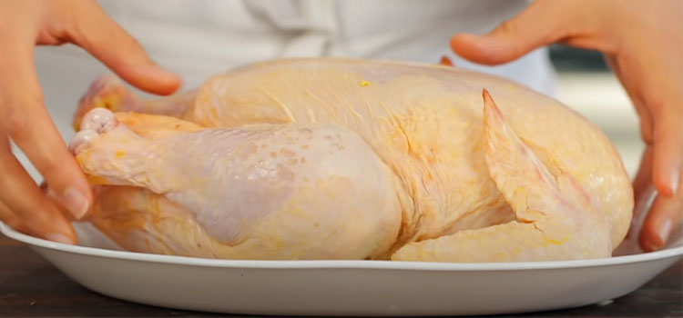 whole raw chicken on a plate